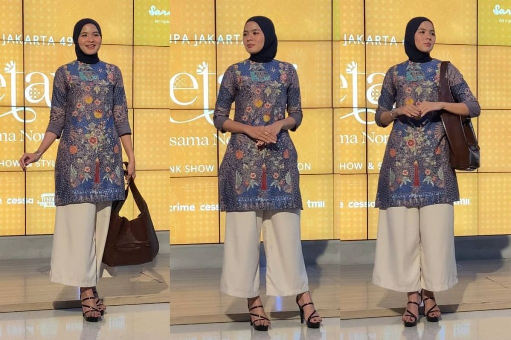 Wanita mengenakan pakaian batik modern yang dipadukan dengan celana netral dan aksesori minimalis.